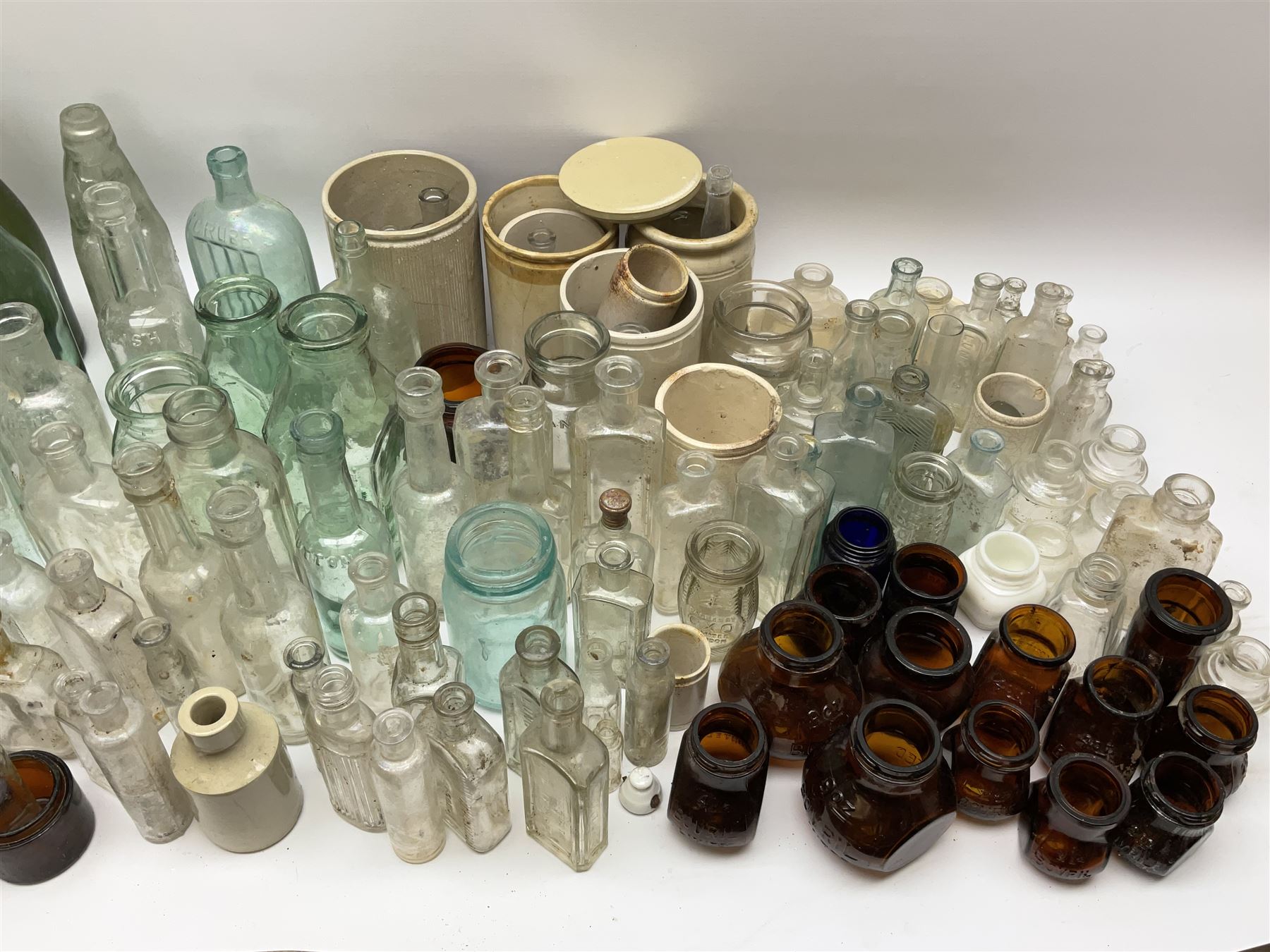 A collection of assorted glass bottles, of various size and form, mostly clear and green glass examples, plus a small group of Stoneware jars. 