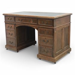 Victorian oak pedestal desk, the rectangular top with inset green leather writing panel and decorative gilt border, over a central frieze drawer flanked by two short drawers, twin pedestals each fitted with four drawers with brass handles, arched kneehole opening, standing on moulded plinth bases