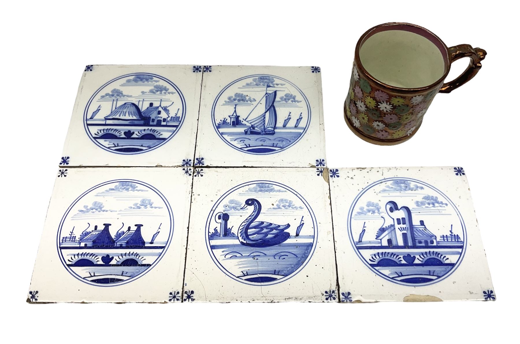 Five 19th century blue and white Delft tiles, each decorated with a central circular panel, containing buildings, boat, and swan, and a Victorian lustre mug decorated with polychrome flowers, tiles H13cm W13cm. 