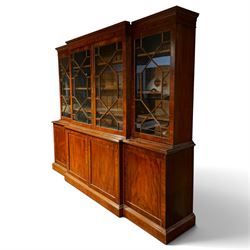 Fine Regency mahogany breakfront library bookcase, the stepped and moulded cornice over four astragal glazed doors enclosing adjustable shelves, the projecting central lower section with a pair of panelled doors enclosing three graduated drawers with brass inset handles above two deep zinc-lined cellarette compartments, flanked by panelled cupboard doors enclosing shelves, the figured mahogany fronts with ebony line inlay, on moulded plinth bases