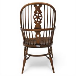 Late 19th century stained elm and beech Windsor armchair, the arched hoop back with pierced wheel splat above shaped lower splat between turned spindles, shaped arm rail on turned supports, saddle seat, raised on turned legs united by a crinoline stretcher