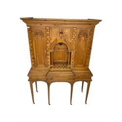 20th century pine architectural collector's cabinet on stand, projecting dentil cornice over various compartments, central recessed arch with turned pillar supports and sloped arch pediment, fitted with four cupboards, false brickwork uprights to front and corners, central hidden drawer revealing cube work surface, lower moulded plinth, the stand with foliate carved mouldings, on six square tapering supports with brass castors