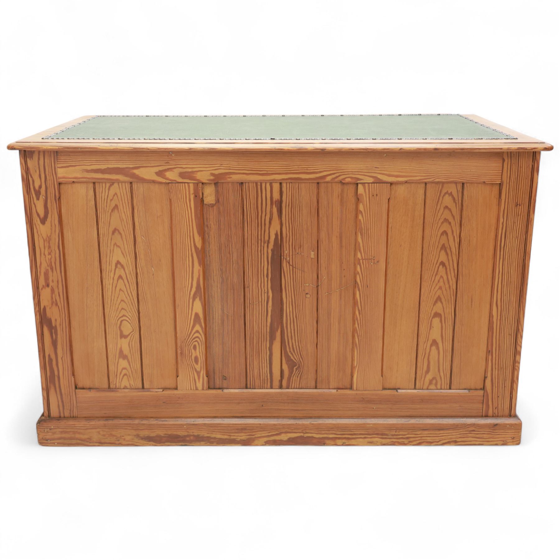 Contemporary stripped and waxed pine pedestal kneehole desk, rectangular top inset with green leather writing surface with brass studded edge, fitted with nine drawers with brass knob handles, above a plinth base on recessed castors