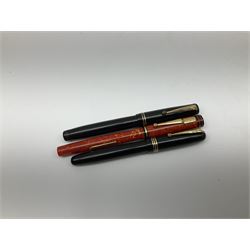 Vintage Swan Mabie Todd lever fill fountain pen in coral red, the nib a/f marked 14K, together with two further vintage Swan Mabie Todd fountain pens, the first example with lever fill, the other leverless, each with black body, one with nib marked 14ct, (3) 