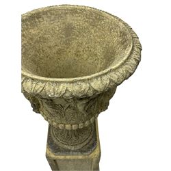 Pair of classical design cast stone Campana-shaped garden urns, the foliage moulded rim over the main body decorated with figural festive scenes, gadrooned underbelly with mask handles, foliate moulded moulded foot, raised on square pedestals with recessed panels and stepped moulded skirt