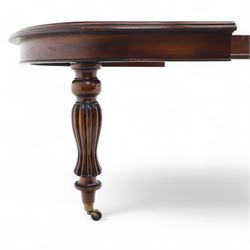 Victorian mahogany extending dining table, rounded rectangular top with moulded edge, pull-out action fitted with two additional leaves, raised on four reeded and fluted baluster legs with brass caps and castors