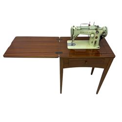Mid-20th century teak sewing table, rectangular top with hinged fold-out extension revealing built-in Singer sewing machine, fitted with single hinged drawer, on square tapered supports; various Singer accessories to include Fashion Discs and Motor Controller