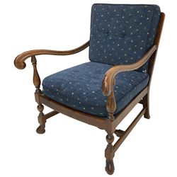 Early 20th century stained beech framed armchair, cane panel back over scrolled arm terminals, raised on turned supports united by turned H-stretcher, with patterned blue upholstered loose back and seat cushions