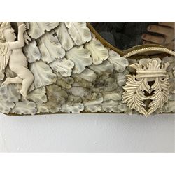 Pair 19th century French Dieppe bone and ivory wall mirrors, the oval bevelled mirror plates within rectangular frames with shaped tops, profusely decorated with ivory leaves, further detailed with carved bone armorial type crest inscribed 'SGOTORVM', putti, fish and mask heads, H81cm W48cm