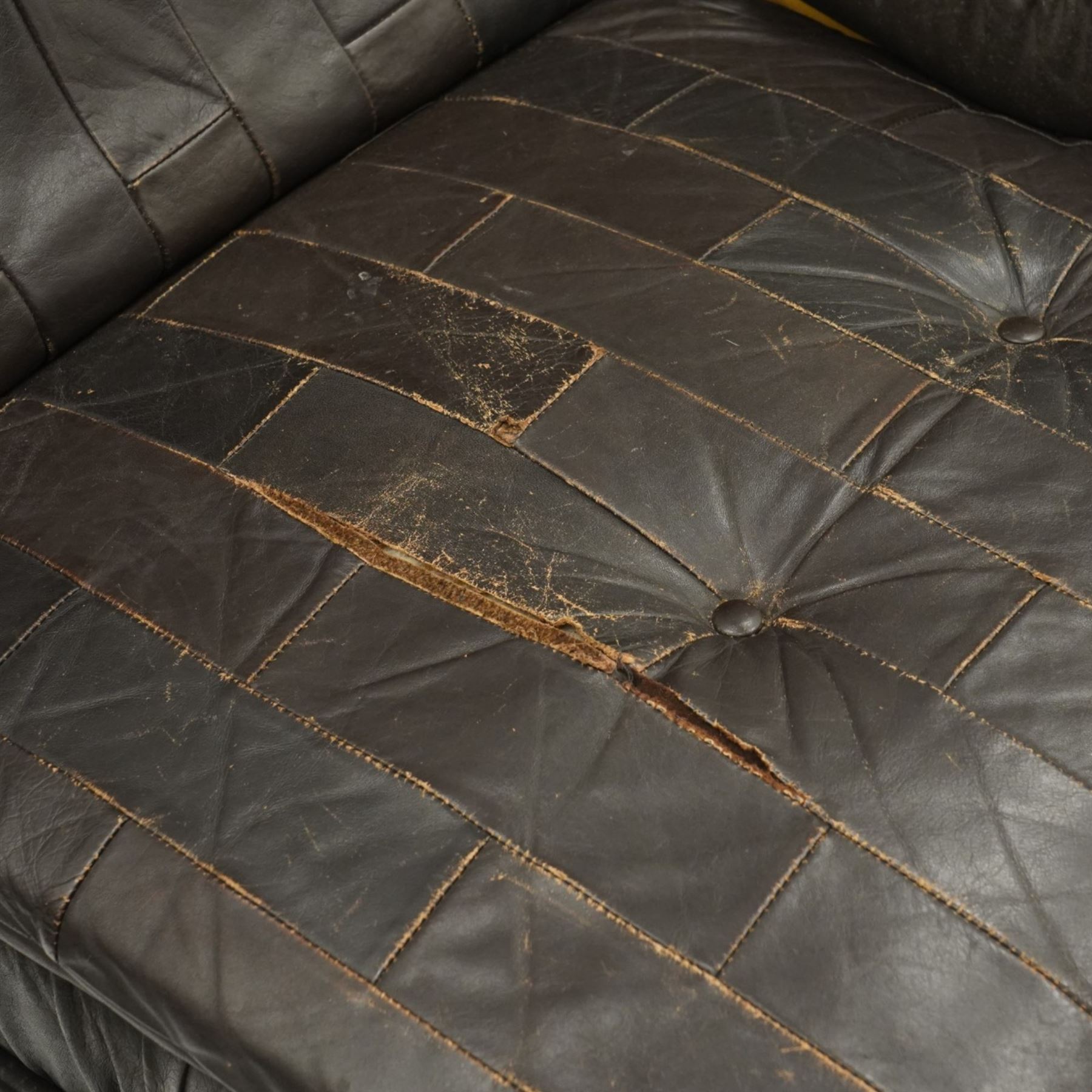 Mid 20th century leather upholstered two-piece sectional sofa with footstool, buttoned back cushions with stitched panel decoration, padded armrests and deep seat cushions, raised on concealed supports