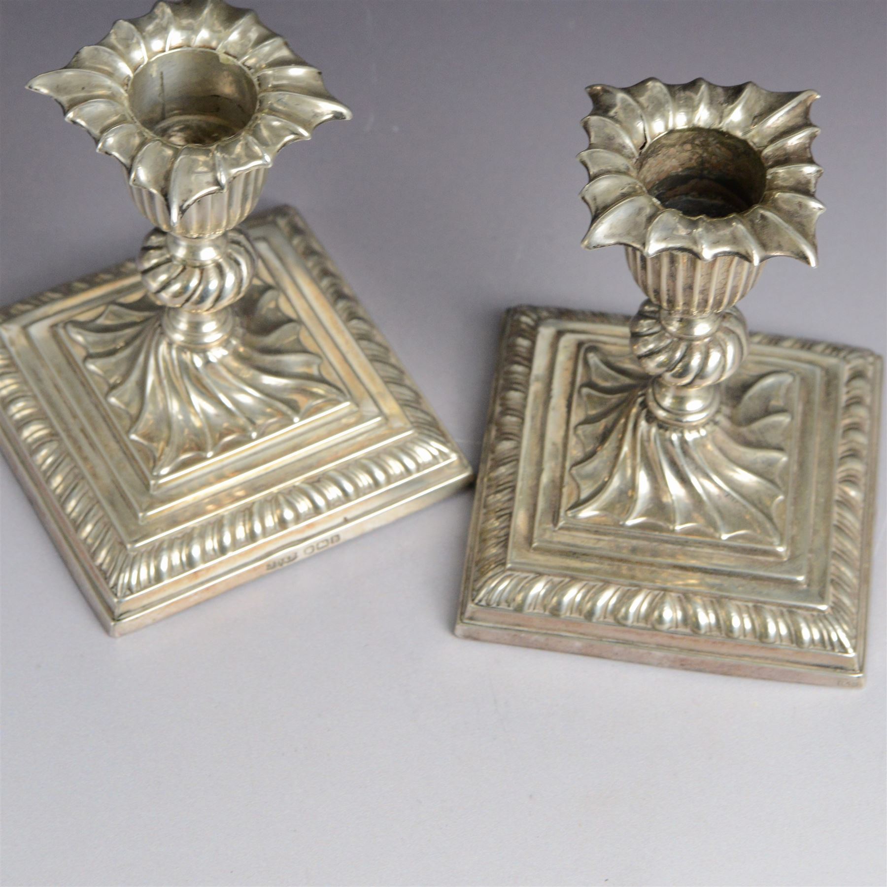 Early 20th century silver pill box, of circular form with pink guilloche enamel lid, hallmarked Deakin & Francis, Deakin & Francis Ltd, Birmingham 1911, together with a commemorative Queen Victoria belt buckle, and a pair of late Victorian dwarf candlesticks with weighted bases, all hallmarked, box D4cm