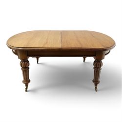 Large Victorian oak extending dining table, the rectangular top with rounded corners and moulded edge, plain frieze over large turned lobed and fluted supports terminating to brass cups and castors, with two additional leaves