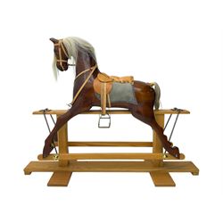 Contemporary carved wooden rocking horse, with leather saddle and bridle, horsehair mane and tail, raised on a pine stand with swing iron supports