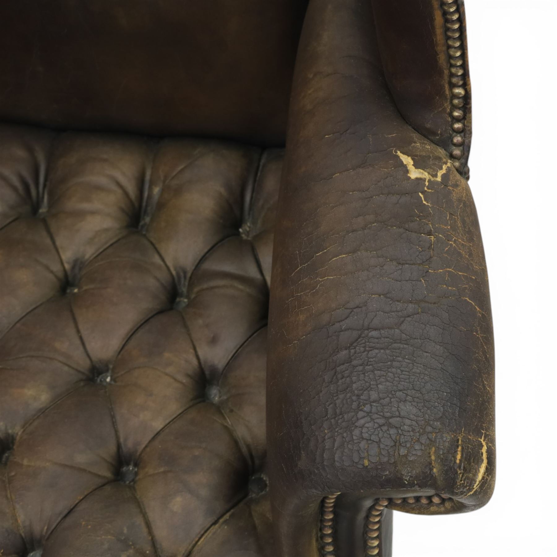 Georgian style leather wing armchair, shaped high back with outscrolled wings above padded arms and deep buttoned seat, close-nailed throughout, raised on square supports united by H-stretcher