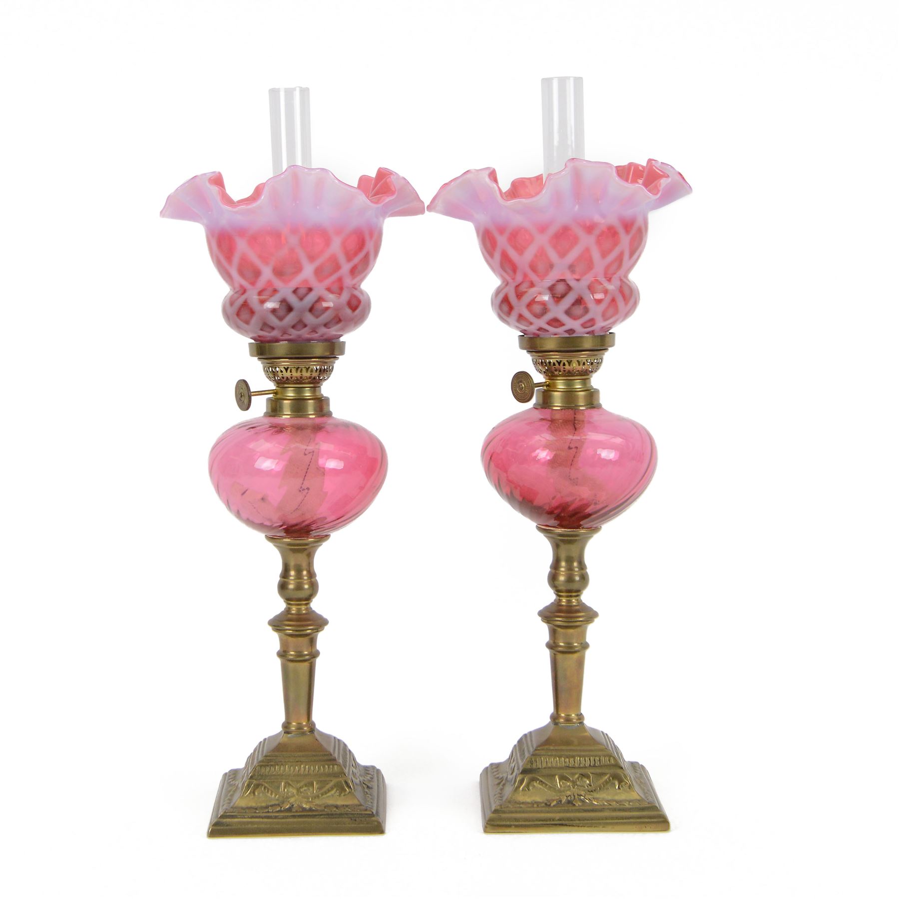Pair of cranberry glass and brass oil lamps, with frilled graduated cranberry glass shade, cranberry reservoir with brass Gaudard burner, upon knopped column  with stepped square base, H46cm
