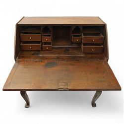 Early 18th century George I oak bureau on original stand, the fall front enclosing an arrangement of correspondence drawers and pigeonholes over central well, fitted with single long drawer below, the shaped apron over cabriole supports with pad feet