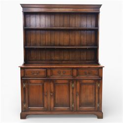 Georgian style oak dresser, the moulded cornice above two open plate racks, upon base with rectangular top above an arrangement of three frieze drawers fitted with brass swan neck handles, and three panelled cupboard doors, upon bracket feet
