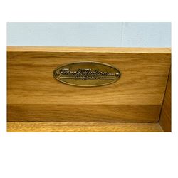 Frank Hudson - contemporary pair of light oak bedside cabinets, each with moulded rectangular top over single drawer above cupboard door with arched panel, on a moulded plinth base with bracket feet