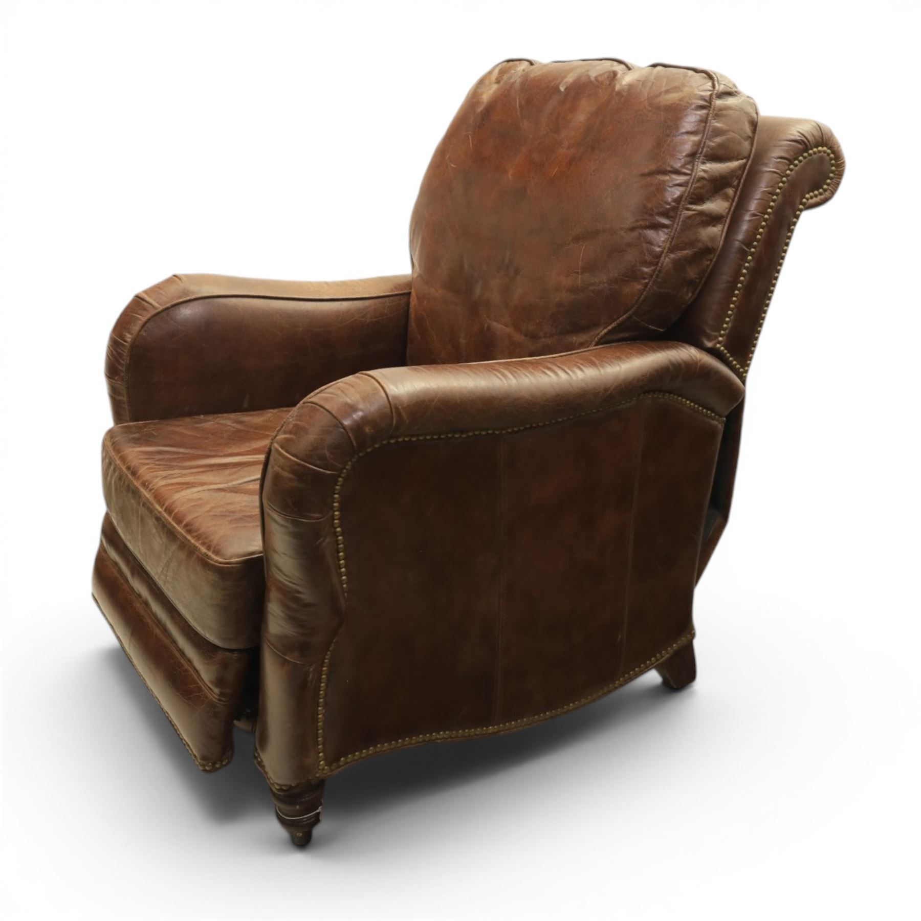 Art Deco style brown leather reclining armchair, scrolled arms with brass studded trim, reclining foot rest and back, fixed back and loose seat cushion,