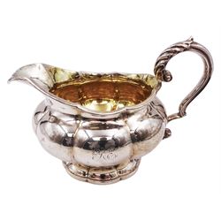 George IV silver milk jug, of squat circular fluted form, with engraved monogram to body, gilt interior and acanthus capped scroll handle, upon lobed foot, hallmarked London 1829, maker's mark worn and indistinct, including handle H10cm