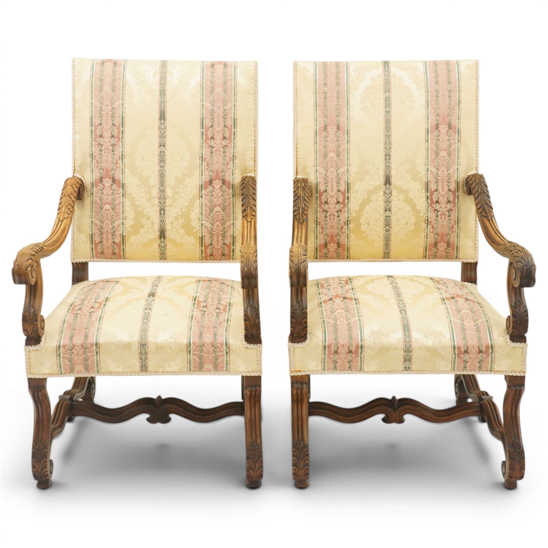 Pair of French Louis XIV design carved walnut open throne armchairs, high back and sprung seat upholstered in foliate damask fabric, acanthus carved scroll form arms over reeded and scrolled supports united by shaped stretcher