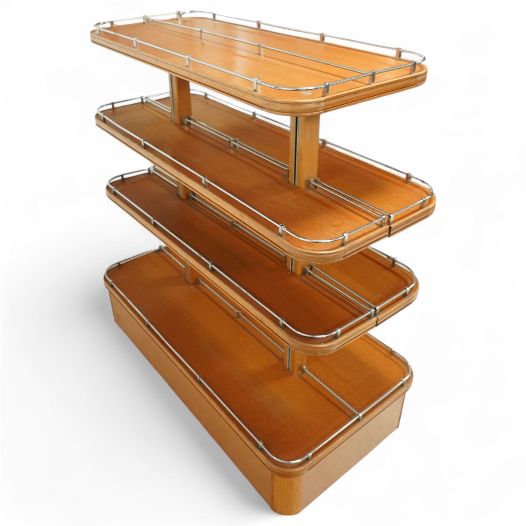 Mid-20th century retail display stand, of stepped rectangular tiered form with four graduated adjustable shelves, each with rounded corners and fitted with tubular chrome safety rails, supported by central chrome-mounted wooden uprights over a plinth base