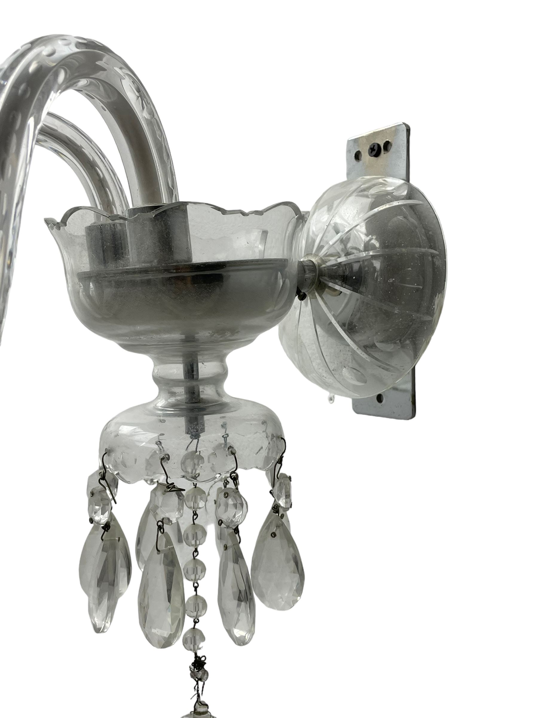 Pair of cut glass two branch wall sconce candelabras, each with S scroll extending branches with shaped and bevelled circular drip trays, hung with pendant drops