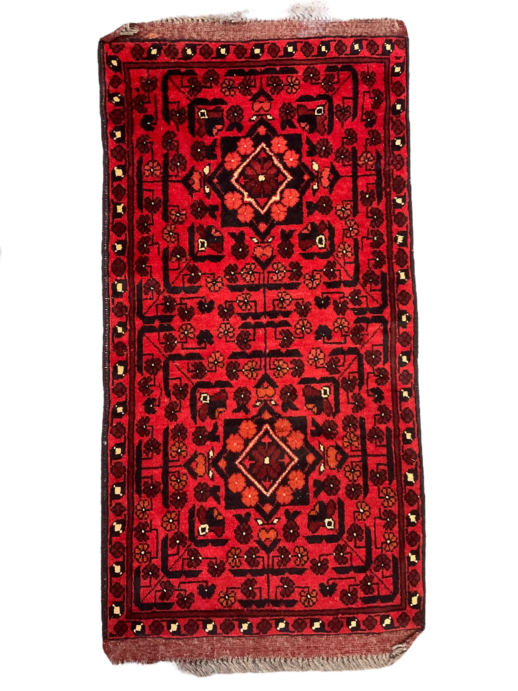Small Persian magenta ground rug, central Mirab with flanking columns enclosing stylised urn motif with trailing foliage, the triple band border with plant motifs (86cm x 46cm); Persian red ground rug, two central floral medallions with extending flower heads, floral decorated border (106cm x 53cm) (2)