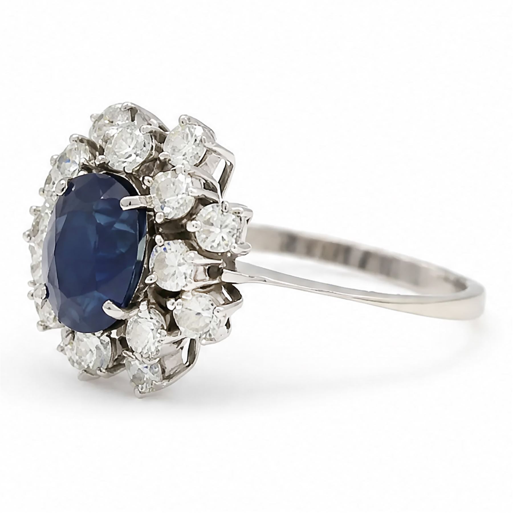 18ct white gold sapphire and diamond cluster ring, single oval cut sapphire of approx 2.10 carat, surrounded by sixteen round brilliant cut diamonds, total diamond weight approx 0.95 carat