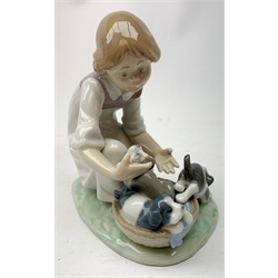 A Lladro figurine, 'This one's mine' Model 5376, H19cm, together with three further Lladro figurines, 'Joy in a Basket' Model 5595, and Sweet Dreams Model 1535, and an example modelled as a boy in hat and scarf, with umbrella and dog by side. 
