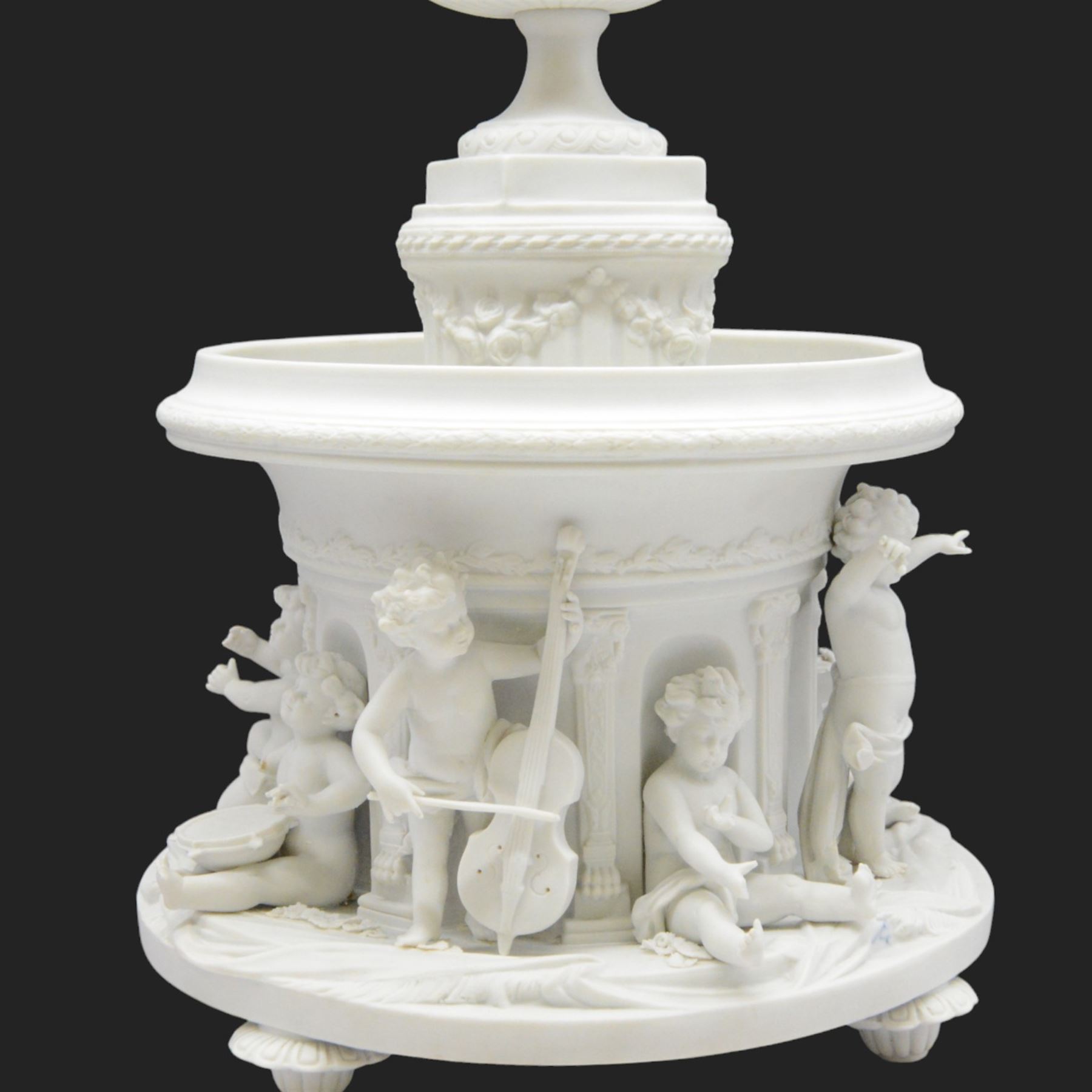 Volkstedt bisque centrepiece, with flower encrusted urn upon a circular reservoir detailed with applied putti playing instruments, marked, H40cm
 
