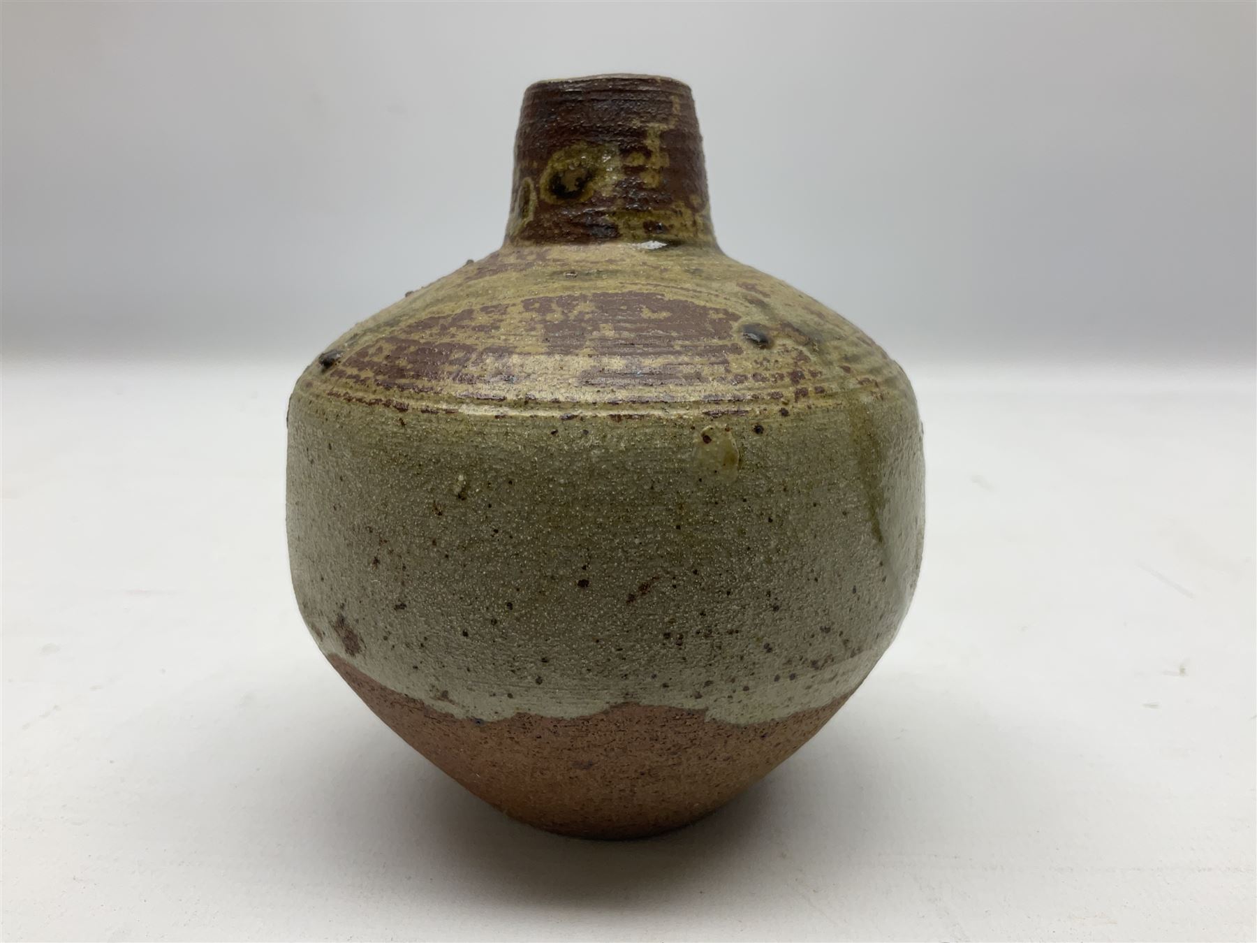 Janet Leach (American, 1918-1997) for Leach Pottery; speckled studio pottery vase of shouldered ovoid form with speckled brown decoration and trailing green and brown glaze upon beige and brown ground, with impressed J.L. monogram and Leach Pottery mark beneath, together with a Jeremy Leach blue speckled lidded circular dish with loop handle, impressed J.L, tallest H11cm