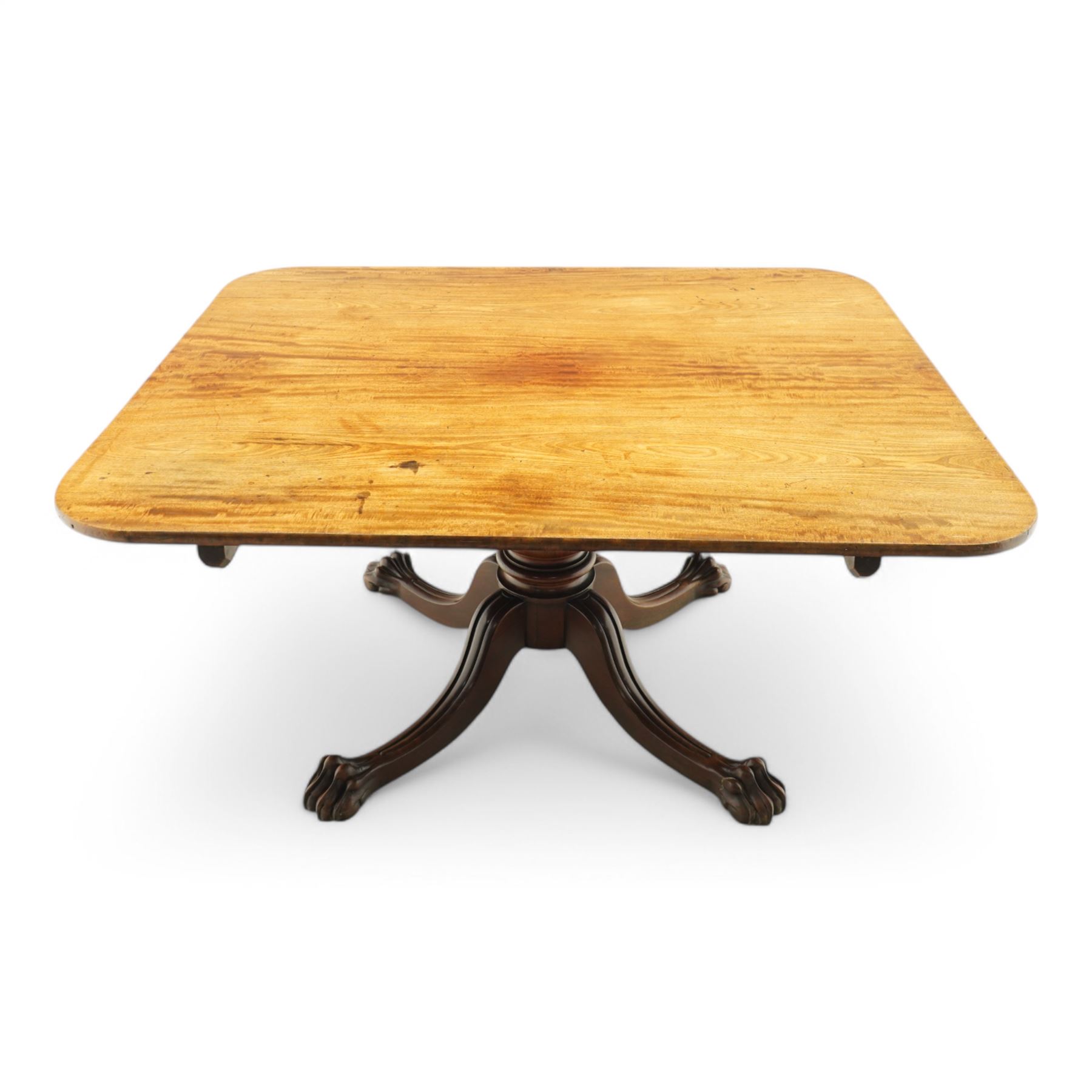 Large Regency mahogany breakfast table, figured rectangular tilt-top with rounded corners, on wide turned pedestal with four out-splayed moulded supports, paw carved terminals with recessed castors 