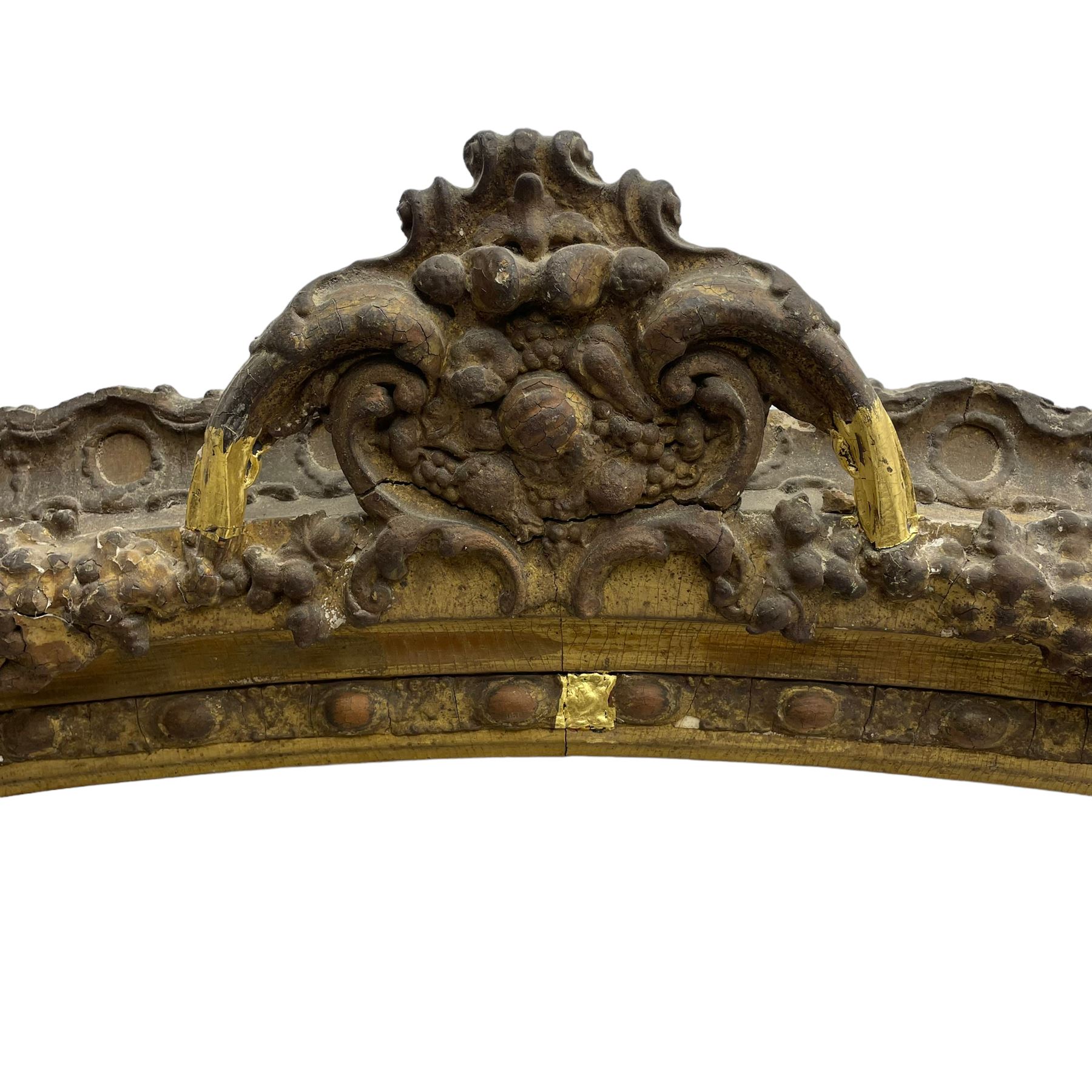 19th century giltwood and gesso moulded picture or mirror frame, the arched cresting rail mounted by central cartouche decorated with foliate scrolls and fruit, the outer frame decorated with scalloped edge and shell mouldings, trailing foliage with flower head and fruit to the central band, egg and dart moulded inner slip