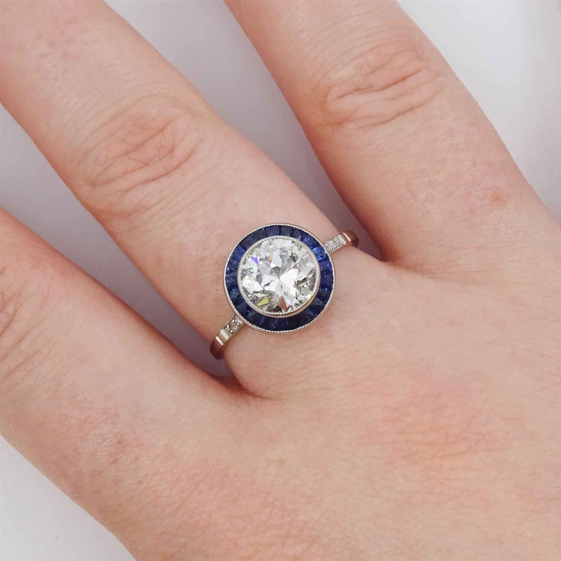 Platinum diamond and sapphire target ring, milgrain set single old cut diamond of 1.53 carat, with calibre cut sapphire surround and rose cut diamond set shoulders, stamped 950