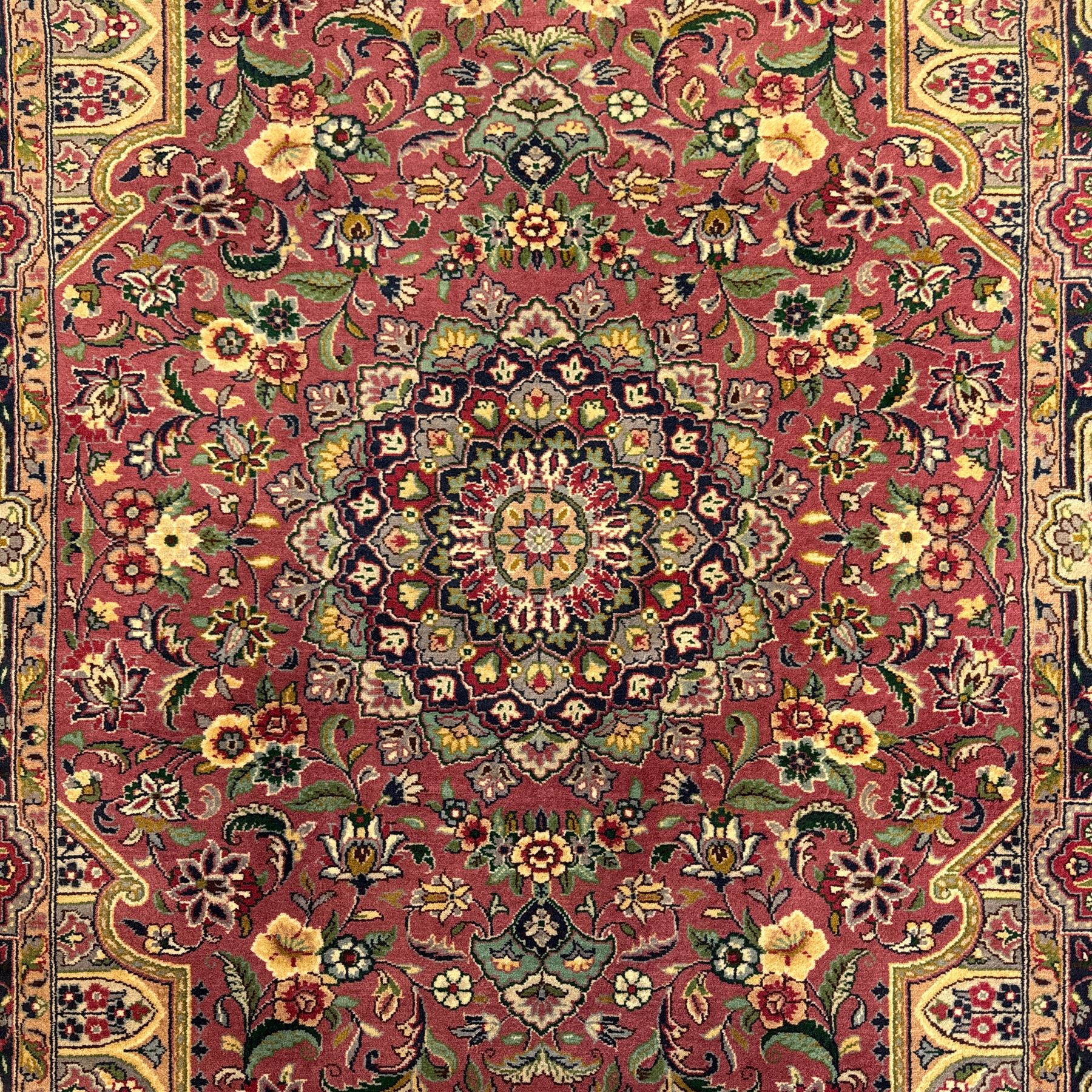 Kashan design hand knotted wool carpet, decorated with an ivory and green floral medallion on a pink ground with scrolling vines, ivory spandrels, multiple navy and ivory borders with stylised flowerheads, from the region of Punjab, Pakistan