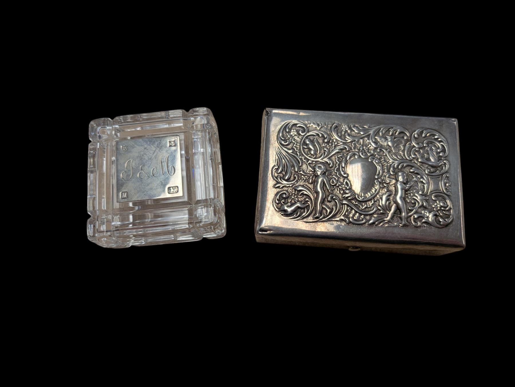Two silver mounted boxes, including embossed example, decorated with cherubs, birds and scrolls, and a square glass example engraved with initials, both hallmarked 