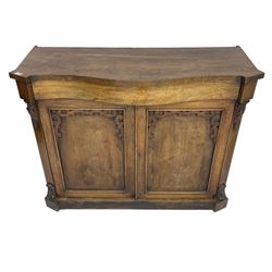 William IV rosewood serpentine chiffonier, fitted with frieze drawer over two panelled cupboard doors with applied C-scroll decoration, flanked by canted uprights with moulded foliate corbels