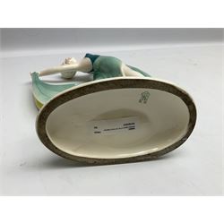 Early 20th century Hertwig Katzhütte figure of an Art Deco lady dancing, wearing a green, blue and yellow dress, stood upon on a domed plinth, with green cat H house printed mark beneath, H32cm