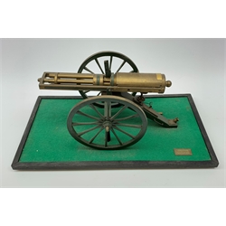 Scratch built brass model of an 1861 Gatling Gun with rotating barrels, hinged cover revealing mechanism, on metal bound wooden spoked wheels and rectangular base L47cm H22cm