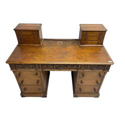 Late 19th century heavily carved oak twin pedestal desk, rectangular top with two raised trinket or correspondence structures each with three drawers, rectangular top over three frieze drawers carved with acorn and oak leaf decoration, each pedestal with three drawers with acorn husk shaped handles