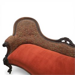 Victorian mahogany framed serpentine sofa, the shaped button upholstered back with central carved foliate cartouche, and scroll arms with carved terminals, over upholstered red seat, upon carved cabriole supports with castors