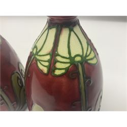 Pair Minton secessionist vases, designed by Leon Solon and John Wadsworth, of ovoid form with everted rim, with tube-lined stylised flower head decoration on a red ground, with printed mark beneath Minton Ltd, No. 30, H13cm