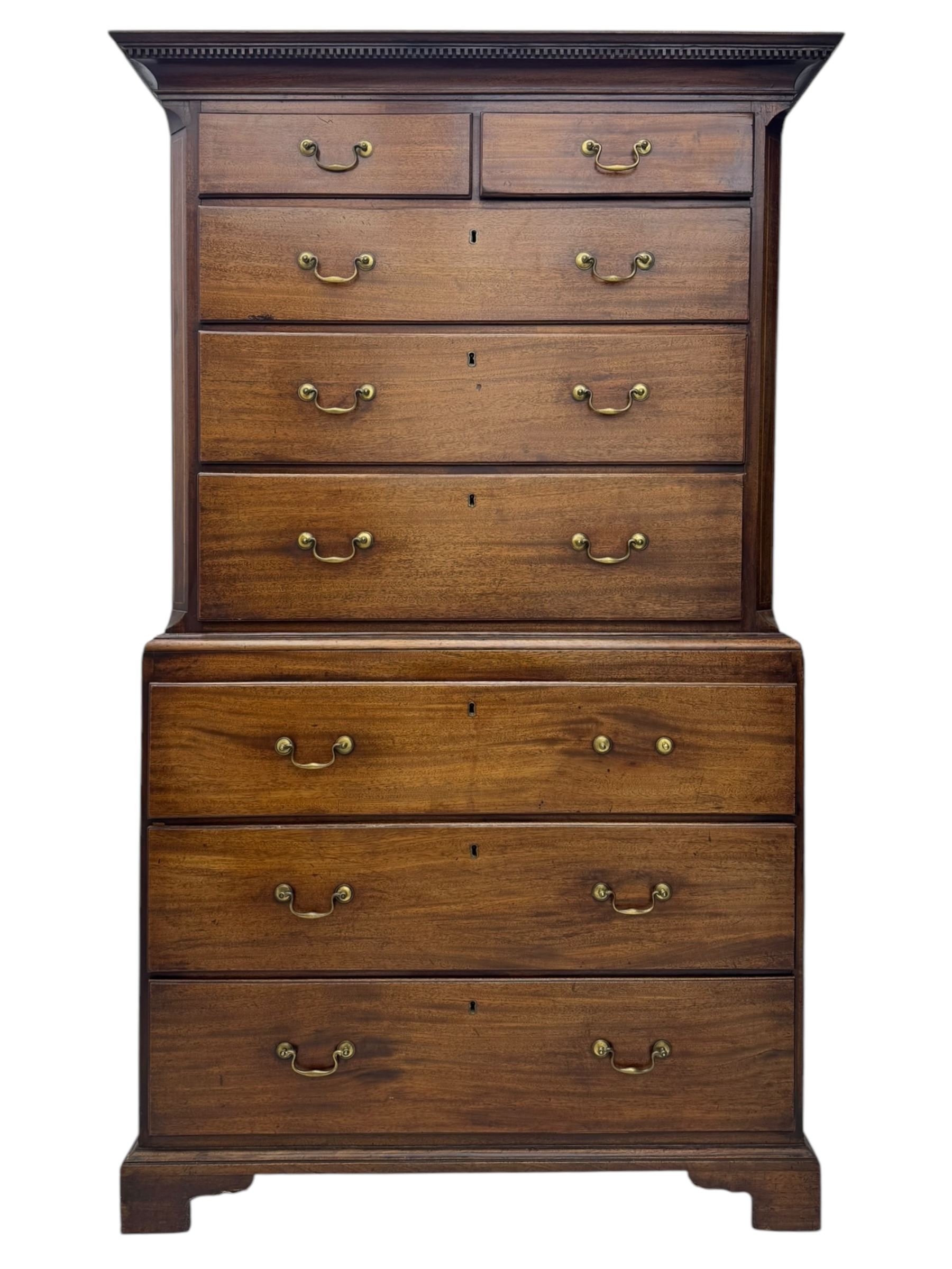 George III mahogany chest on chest, the upper section with two short over three long drawers with swan neck handles flanked by canted corners, inlaid with boxwood stringing below a dentil cornice. The lower section with three long drawers, supported on bracket feet 