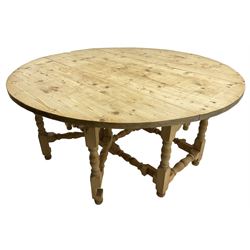 Traditional stripped pine dining table, circular drop-leaf top over double gate-leg action base with turned supports united by turned stretchers