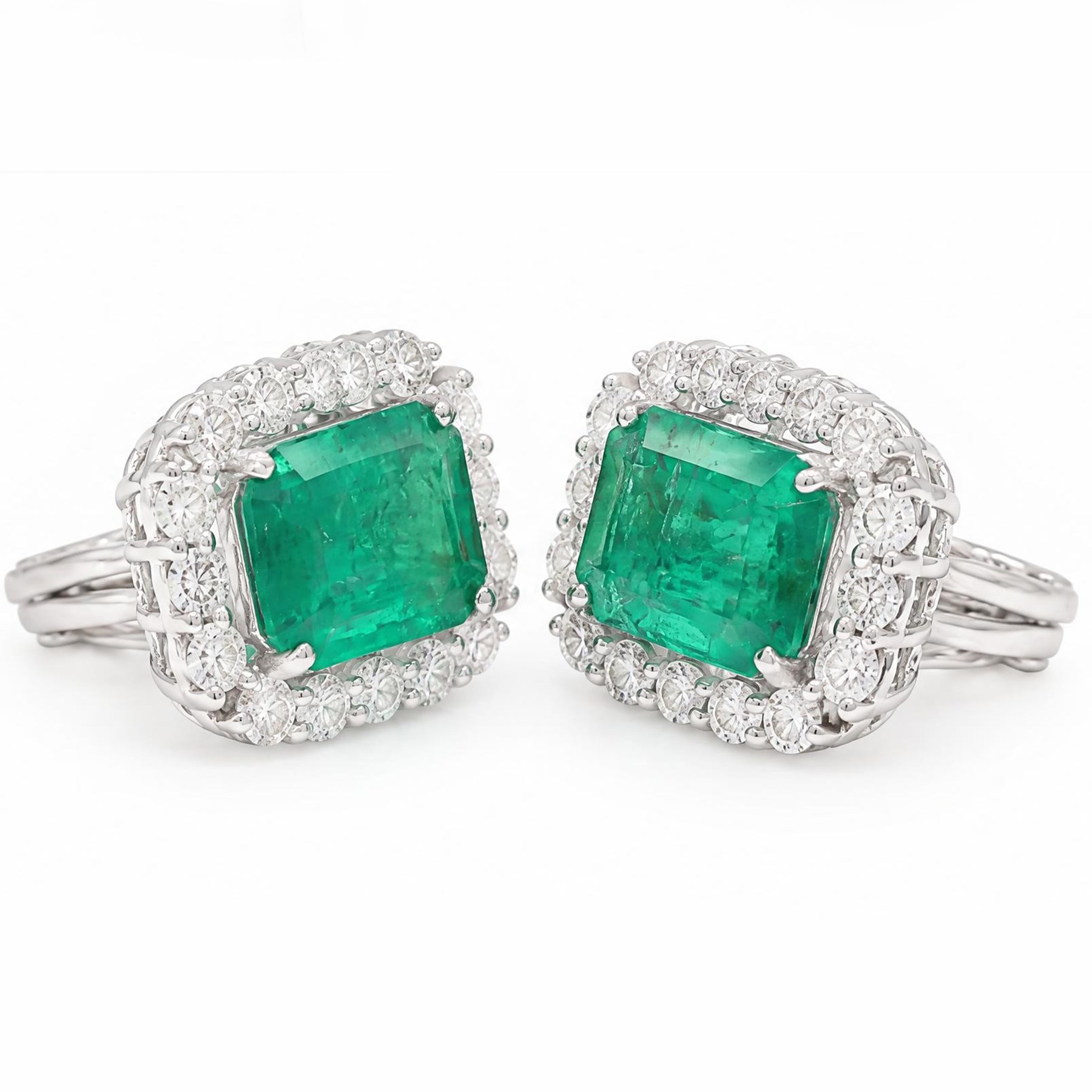 Pair of 18ct white gold emerald and diamond cluster earrings, each stud set with a single octagonal cut emerald and surrounded by sixteen round brilliant cut diamonds, stamped 750, total emerald weight approx 6.90 carat, total diamond weight approx 1.90 carat
