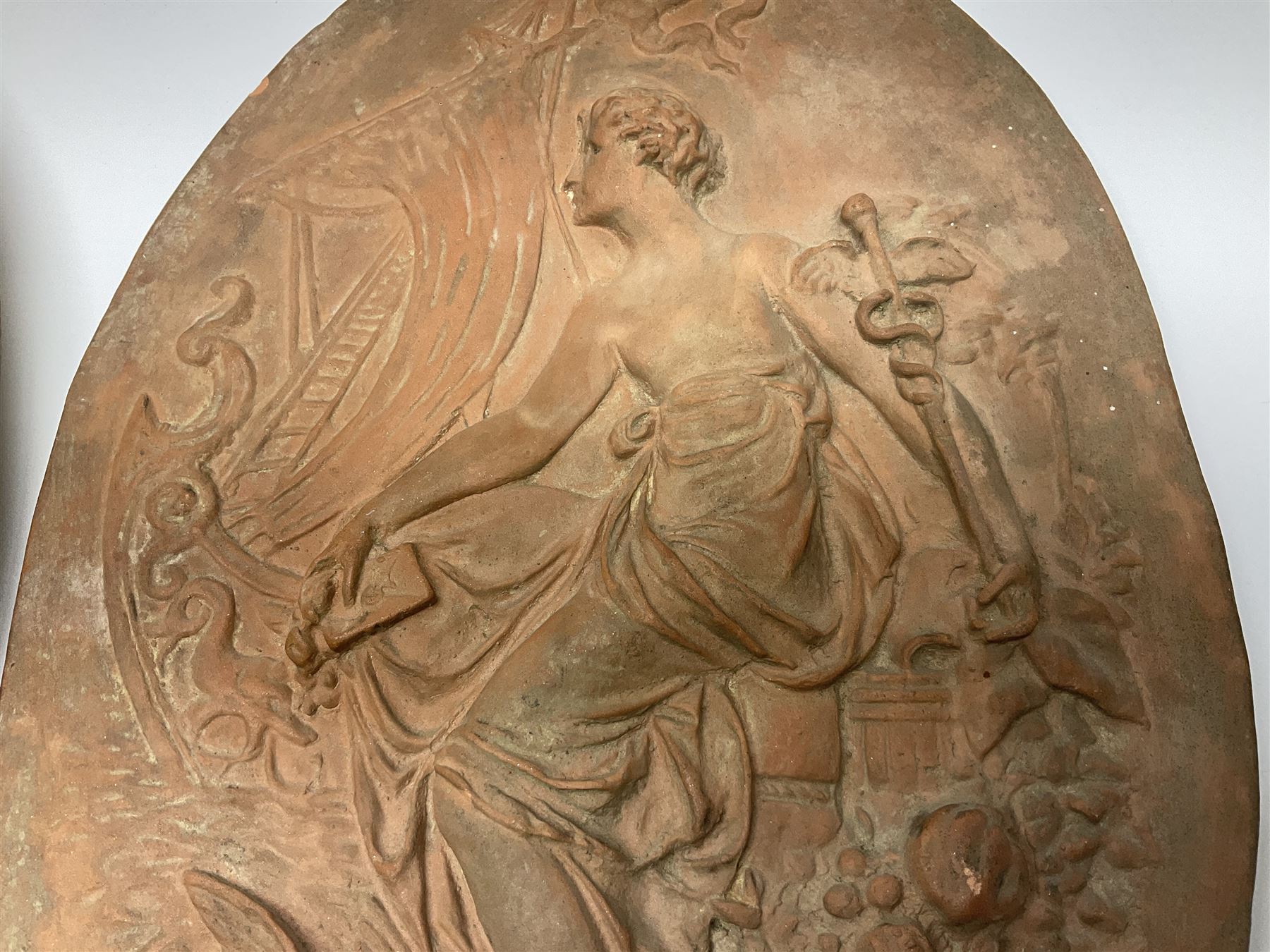 Pair of 19th century classical terracotta relief wall plaques depicting the goddess Hygeia and another goddess, seated holding an ewer, each of oval form, indistinctly signed, each stamped Ferreira verso, H42cm, W30cm