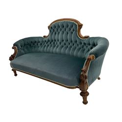 Victorian walnut framed settee, the raised arched back carved with foliate, buttoned back upholstered in blue fabric, c-scroll carved arms supports carved with bell flowers, turned front feet with carved and fluted decoration 