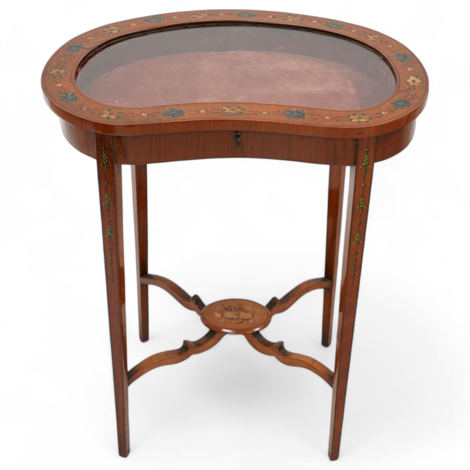 Edwardian satinwood kidney-shaped bijouterie table, hinged lid with glazed panel enclosed by floral painted frame, on square tapering supports decorated with trailing bell flowers, united by shaped stretchers and oval tier painted with ribbon and trumpets 