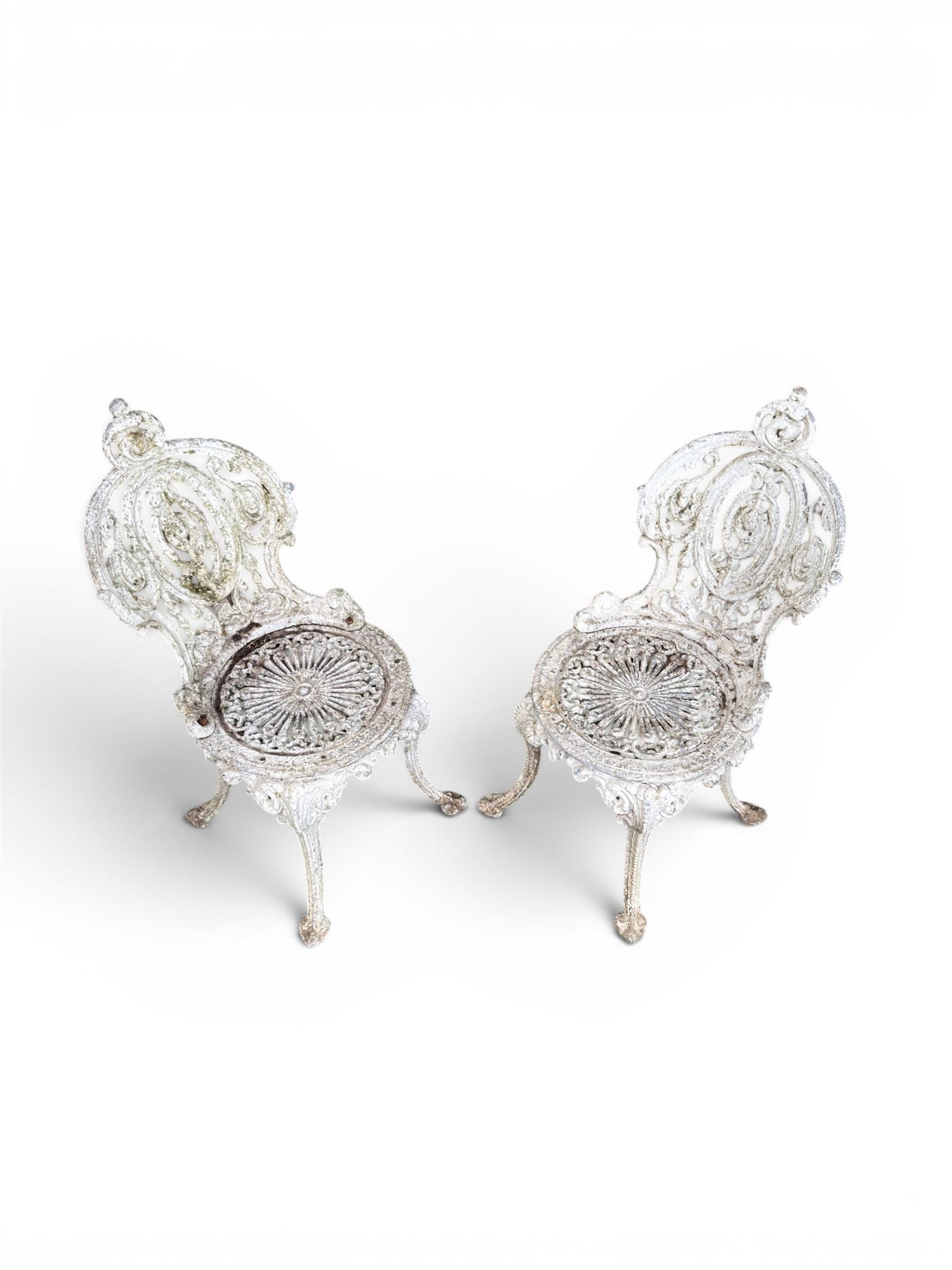 Pair of white painted cast metal garden chairs, ornate reclined backs, circular pierced seats on cabriole legs
